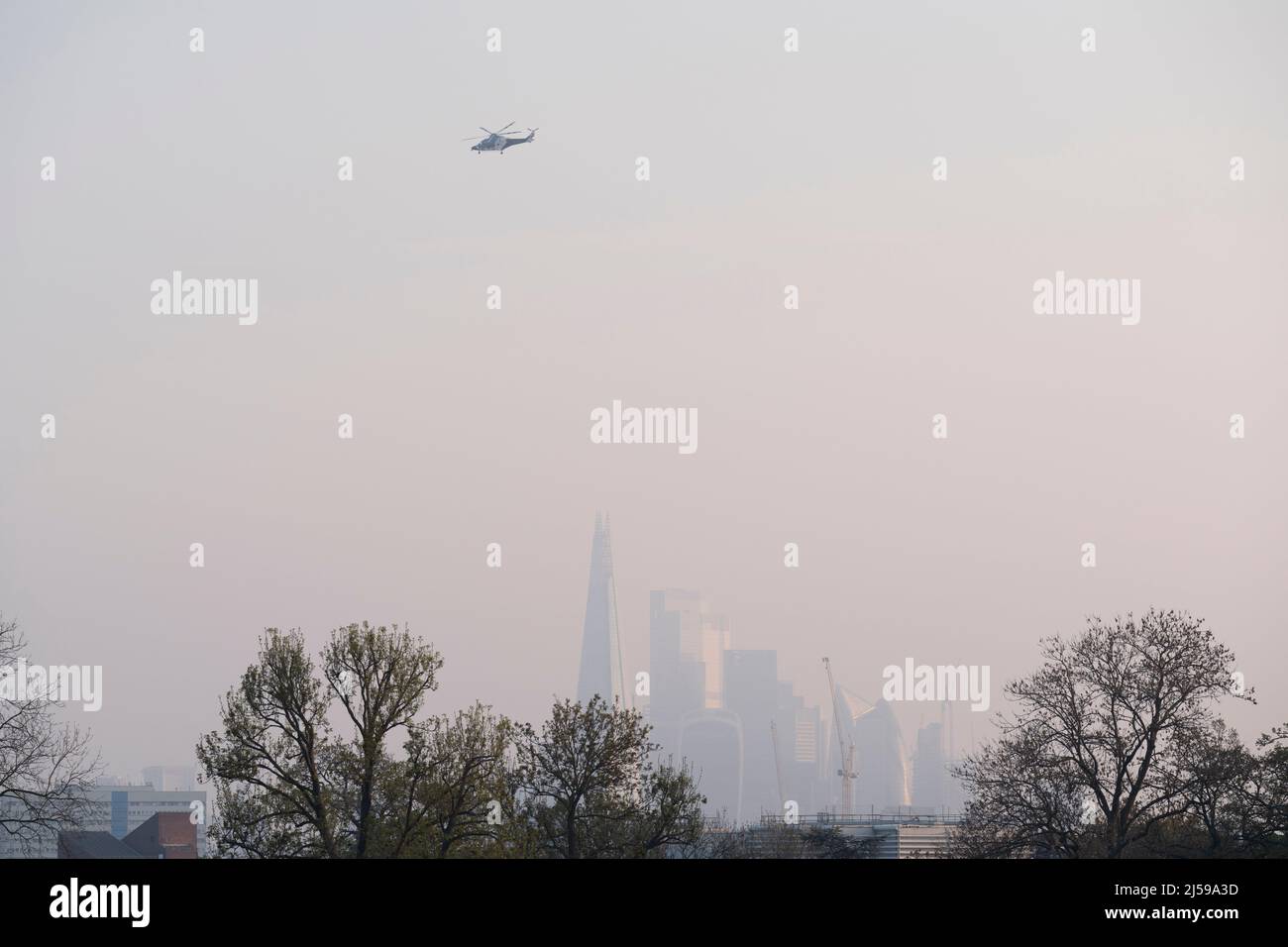 Soon after taking-off from Kings College Hospital in Camberwell, a helicopter with the Kent Air Ambulance flies over the capital, with the Shard seen in the distance, from Ruskin Park, a south London green space in Lambeth, on 21st April 2022, in London, England. Stock Photo