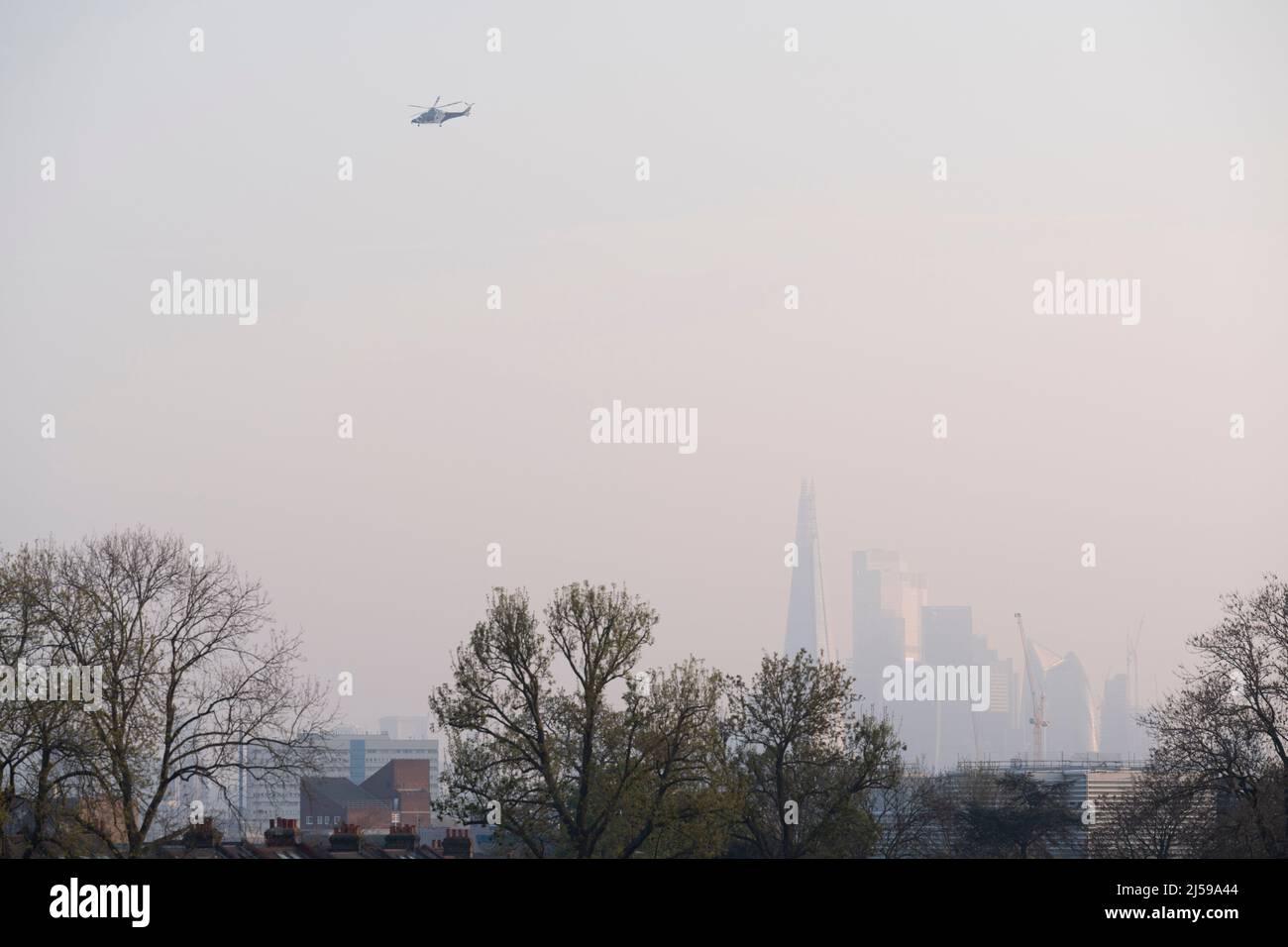 Soon after taking-off from Kings College Hospital in Camberwell, a helicopter with the Kent Air Ambulance flies over the capital, with the Shard seen in the distance, from Ruskin Park, a south London green space in Lambeth, on 21st April 2022, in London, England. Stock Photo