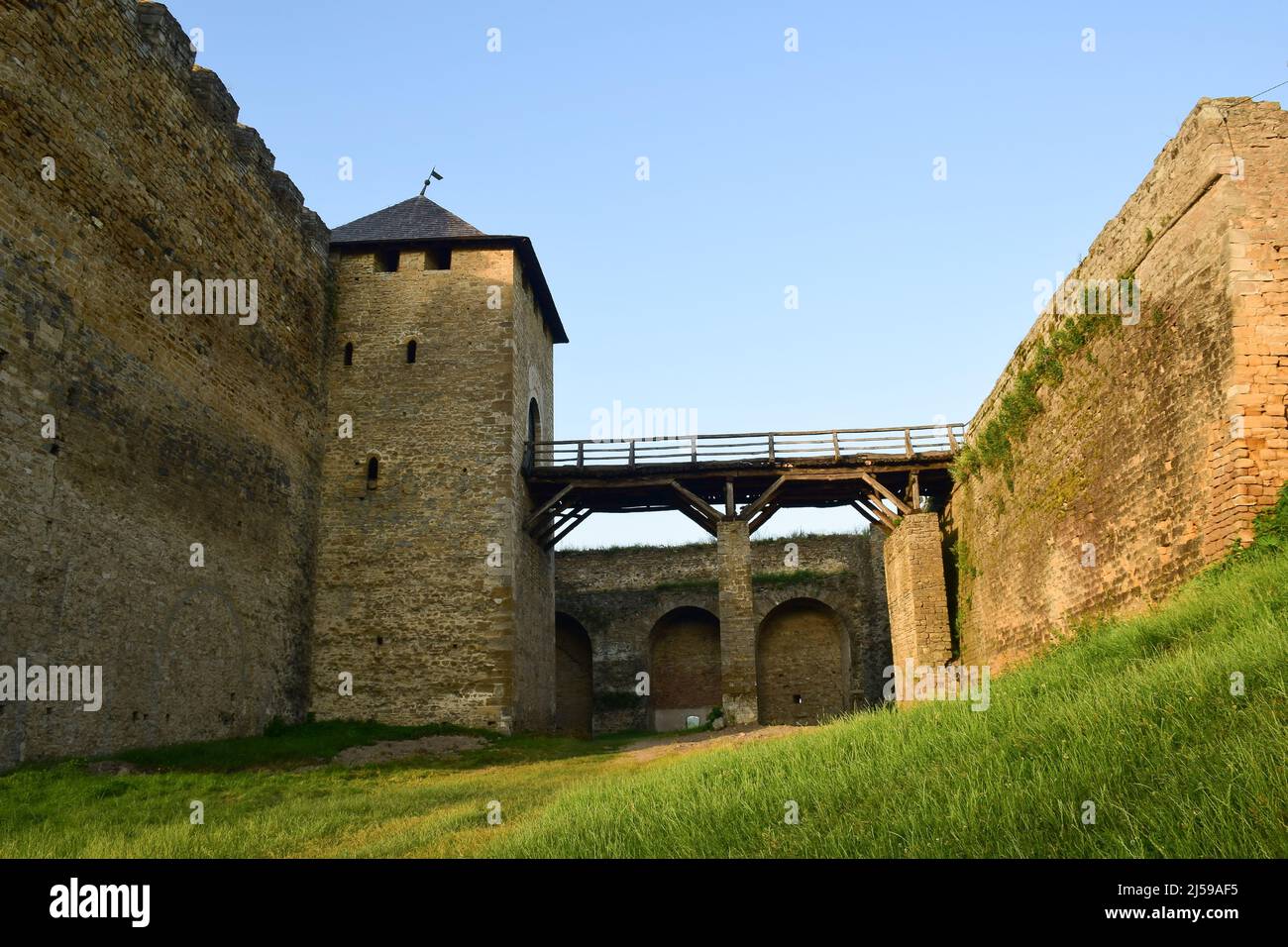 Wooden bridge to the tower of a medieval stone fortress with high battlements and loopholes. View from a low angle Stock Photo