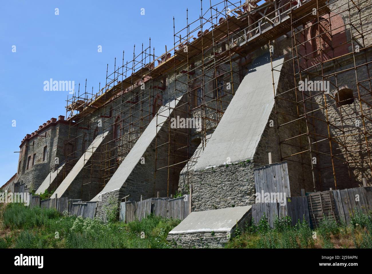 One of the walls of a medieval stone fortress in the construction repair scaffolding Stock Photo