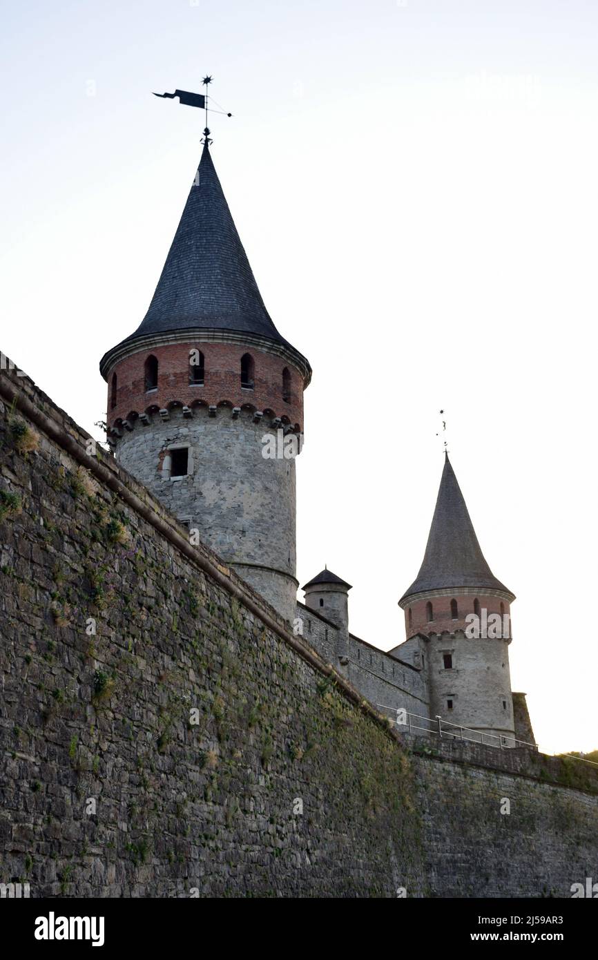 Several towers of a medieval stone fortress with a wall overgrown with ...