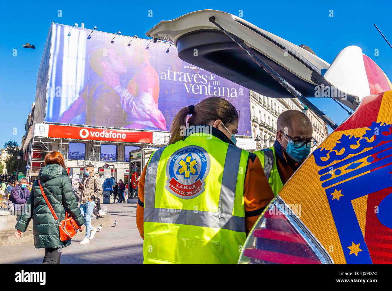SAMUR Protection Civil female and male employees in uniform vests, face masks with their van's trunk opened in Plaza Mayor, Madrid, Spain Stock Photo