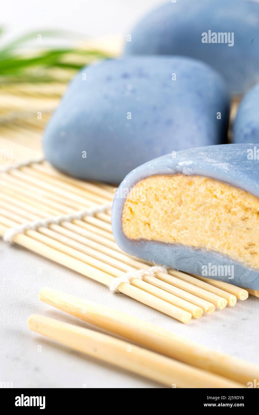 A Japanese mochi lying on a wooden mat on white countertop. Concept of a traditional Japanese rice cake with a maki sudare mat and chopsticks Stock Photo