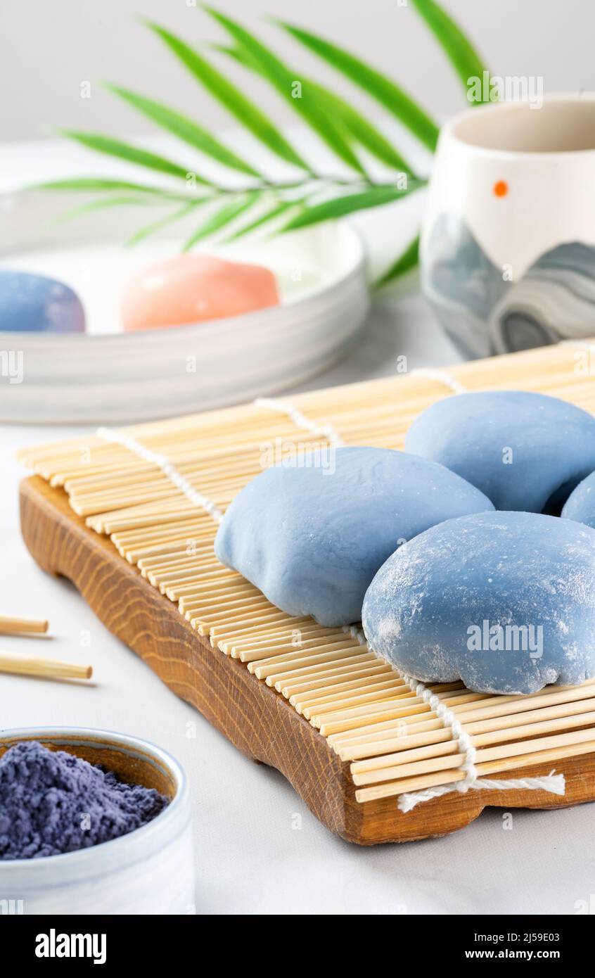 A Japanese mochi lying on a wooden mat on white countertop. Concept of a traditional Japanese dessert on the kitchen table. Asian rice cake Stock Photo