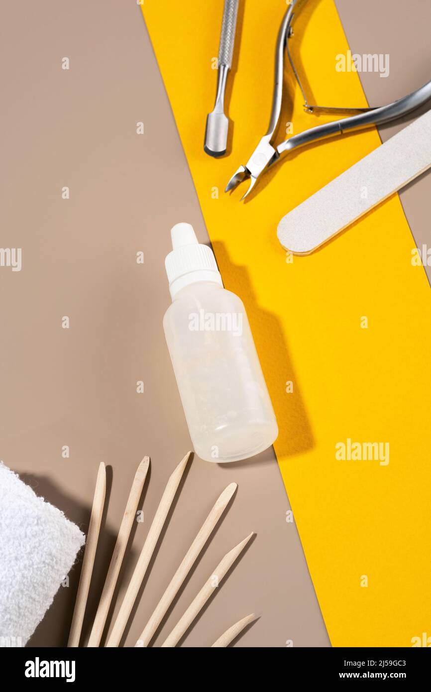 A set of manicure tools, sticks on a background of orange and coffee colors. A bottle of cuticle gel lying on an orange background. Nail care, design Stock Photo