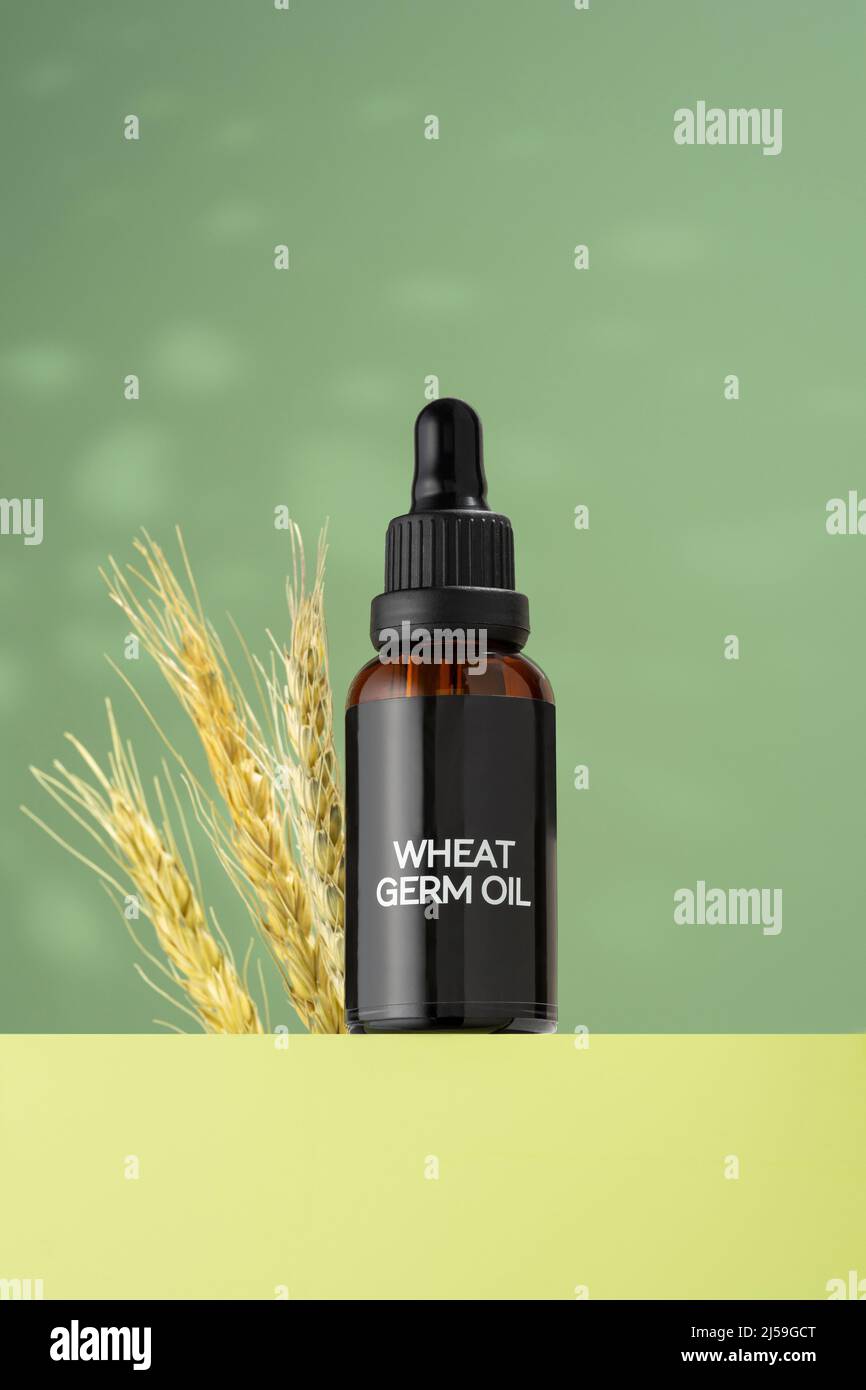 Glass bottle of wheat sprouts oil with dropper, standing on green