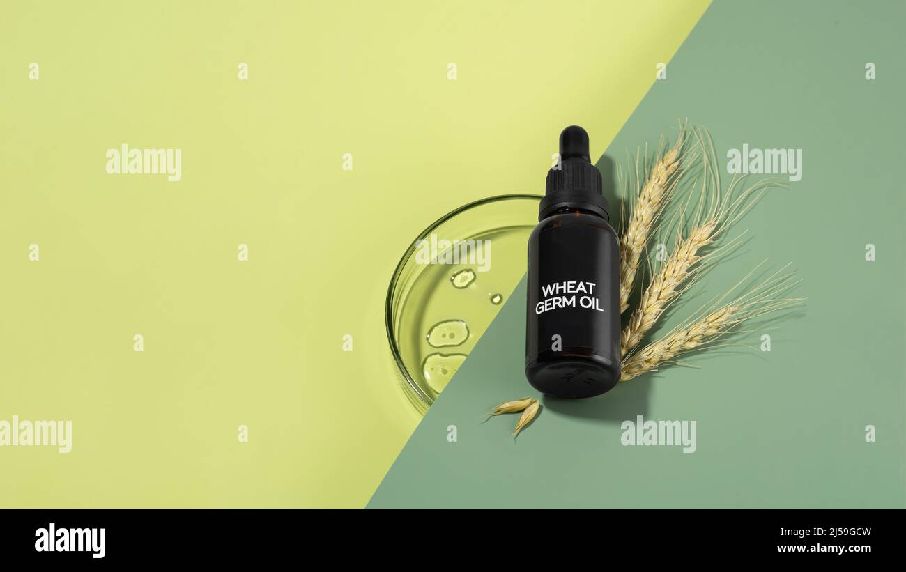 Glass bottle of wheat sprouts oil with dropper laying on a green