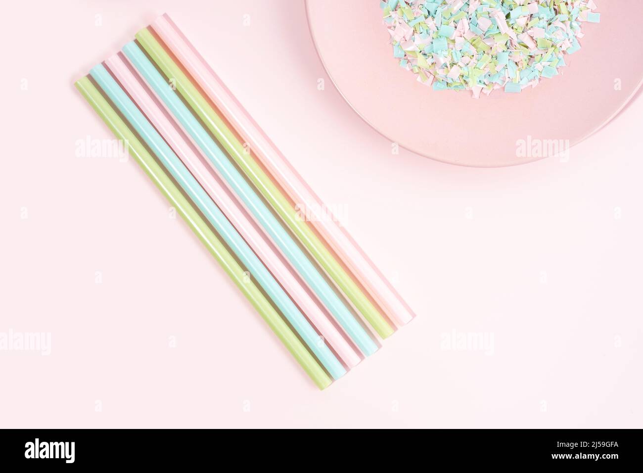 Drinking straws and plate full of microplastics on a pink background. Impact of micro plastic on the food chain. The idea of micro plastic pollution. Stock Photo