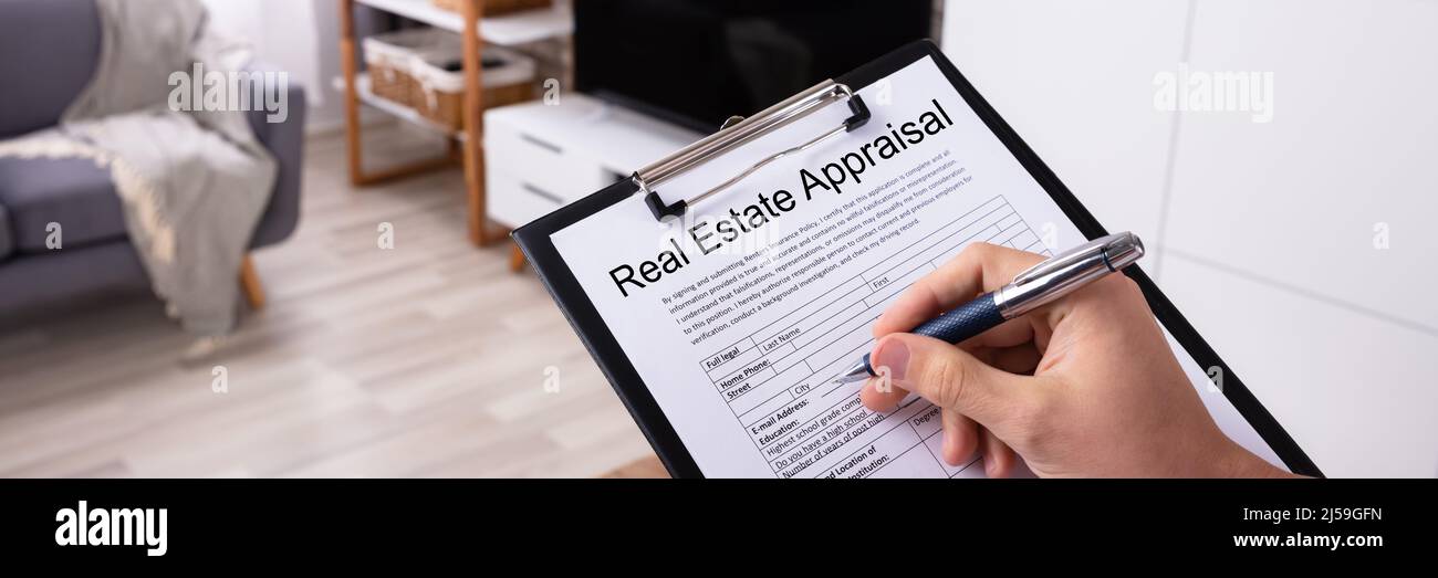 Closeup Of A Man's Hand Filling Real Estate Appraisal Form At Home