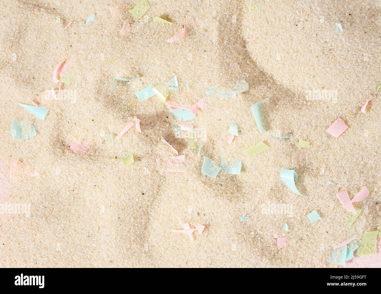 Conceptual composition of microplastics and coastal sand. The impact of microplastic on nature. The idea of micro plastic pollution. Stock Photo