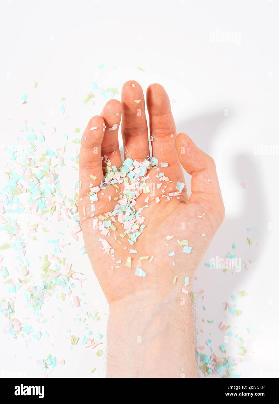 Shot of microplastics lay on people hand. Concept of water pollution and global warming. The idea of environmental damage. Top view, white background. Stock Photo