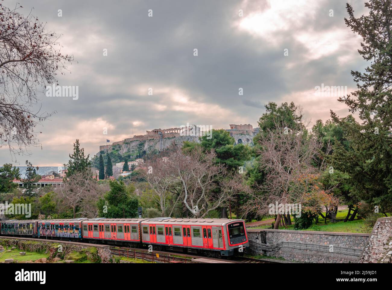 Athens, Greece - January 30 2022: The Metro of Athens running along the Ancient Agora with the Acropolis in the background. Stock Photo