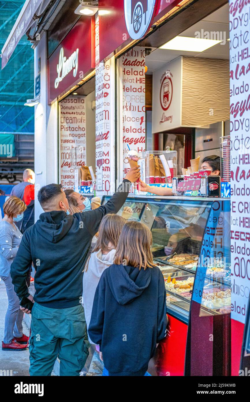 A man gets a cone ice cream from a small business located in the old town. Other people are seen out and about the travel scene. This area is a famous Stock Photo