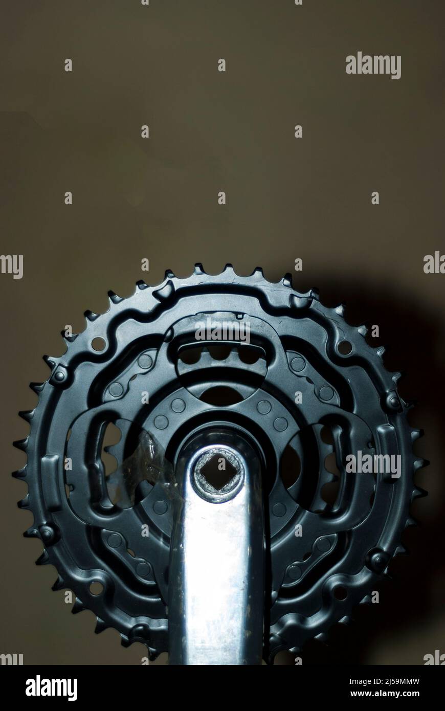 black metallic mountain bike chainring with dark background in vertical with area for copy paste Stock Photo