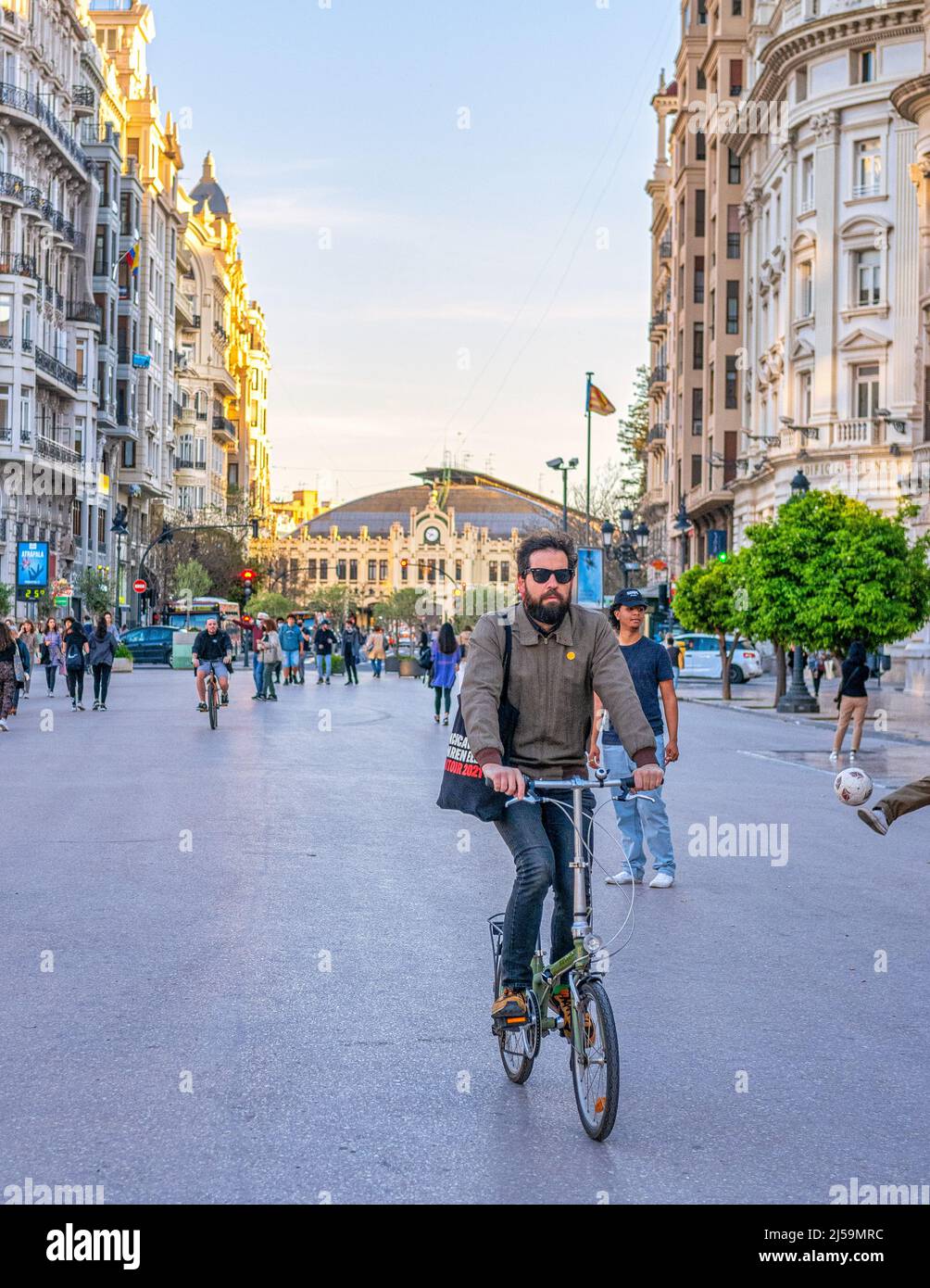 A man is seen riding a bicycle in the Plaza del Ayuntamiento or City Hall Plaza. The town square is surrounded by majestic colonial style buildings. O Stock Photo
