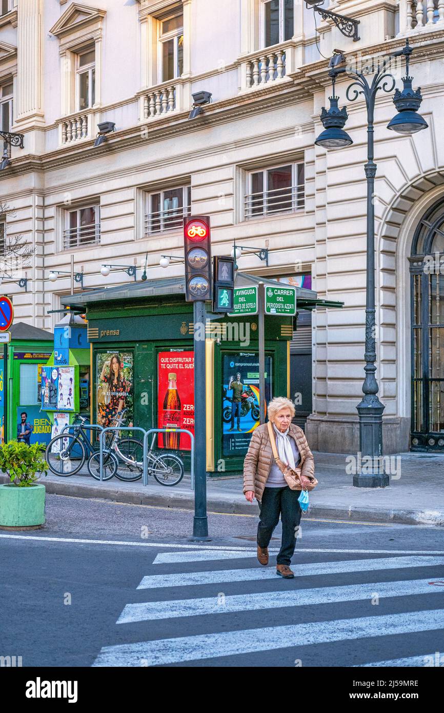 A senior woman start to cross the street using a crosswalk in the old town. This residential district is a famous place and a tourist attraction. Stock Photo