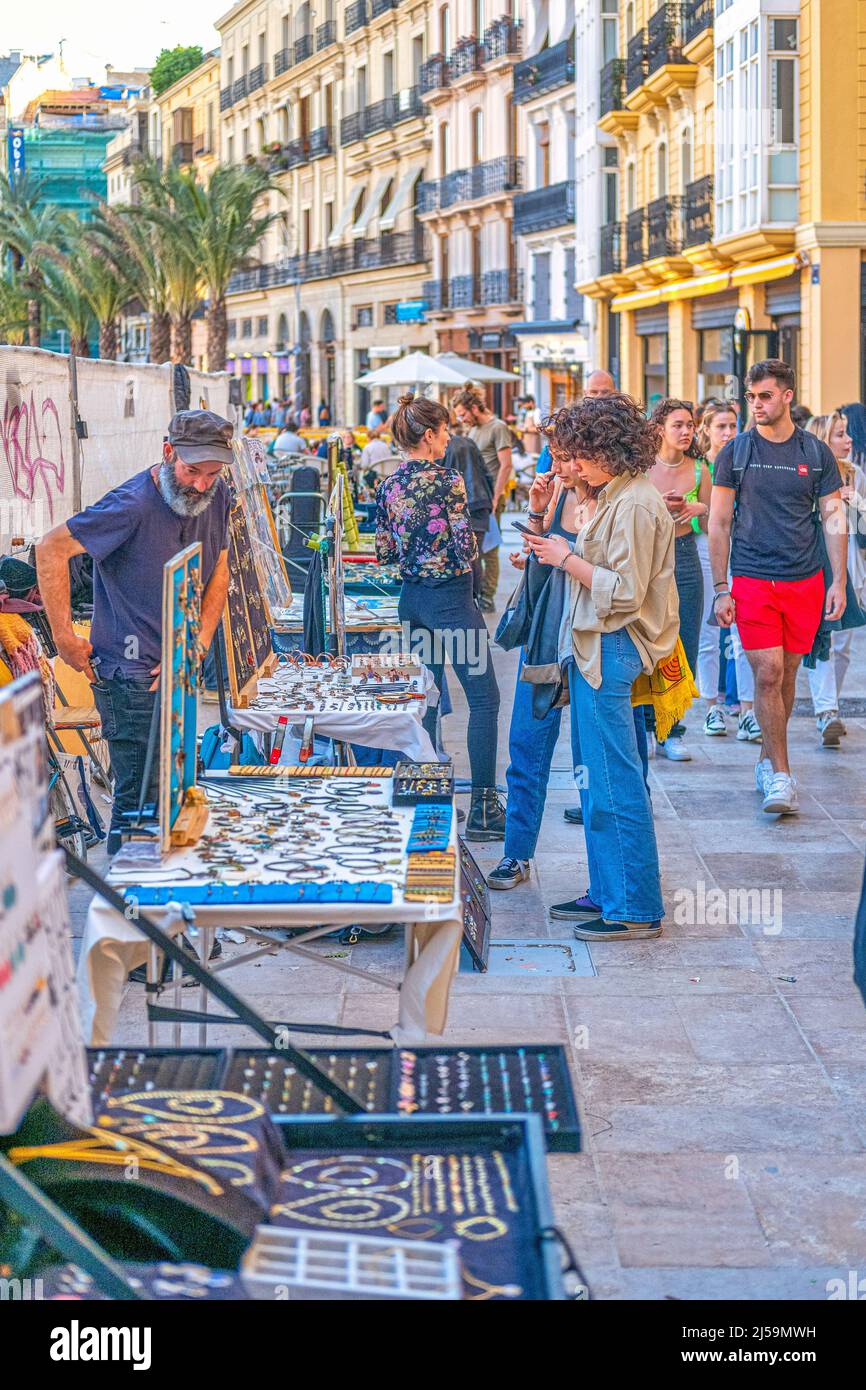 Souvenir street vendors are seen in the city hall plaza. A group of tourists browse the merchandise. This area is a famous place and a major tourist a Stock Photo