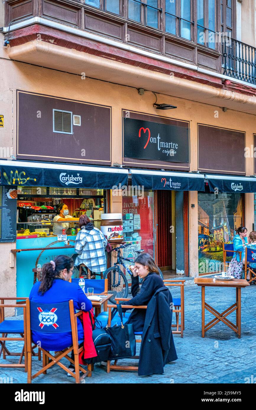 People or tourists are seen sitting in a patio table in the Montmartre creperie. This small business is located in the old town. This centric district Stock Photo