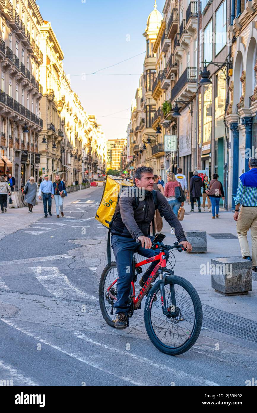 A man is seen delivering food while riding a bicycle in the old town. This centric district  is a famous place and a major tourist attraction. Colonia Stock Photo