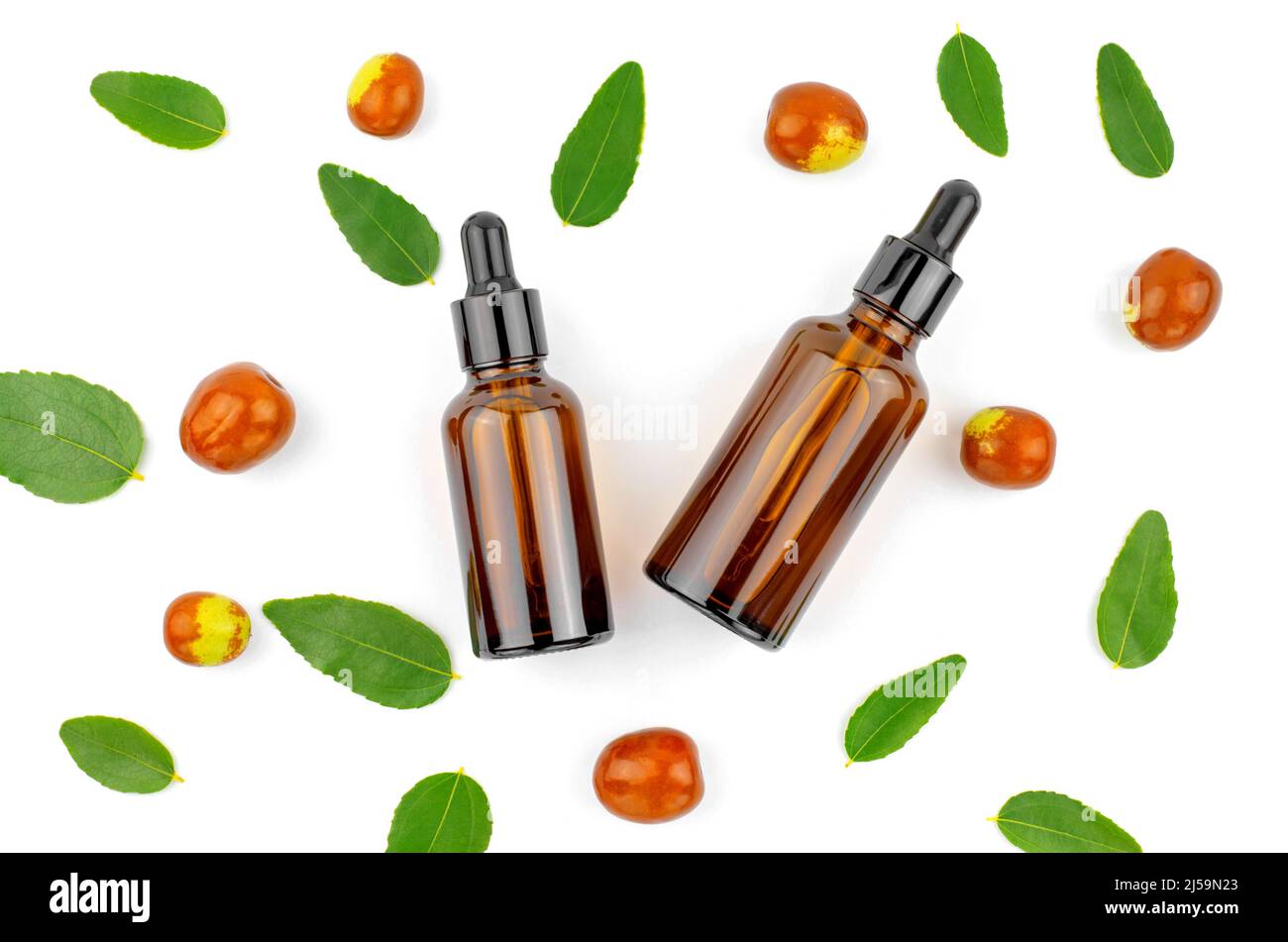Bottles with jojoba oil on a white background with jojoba fruits and leaves. Skin care Stock Photo