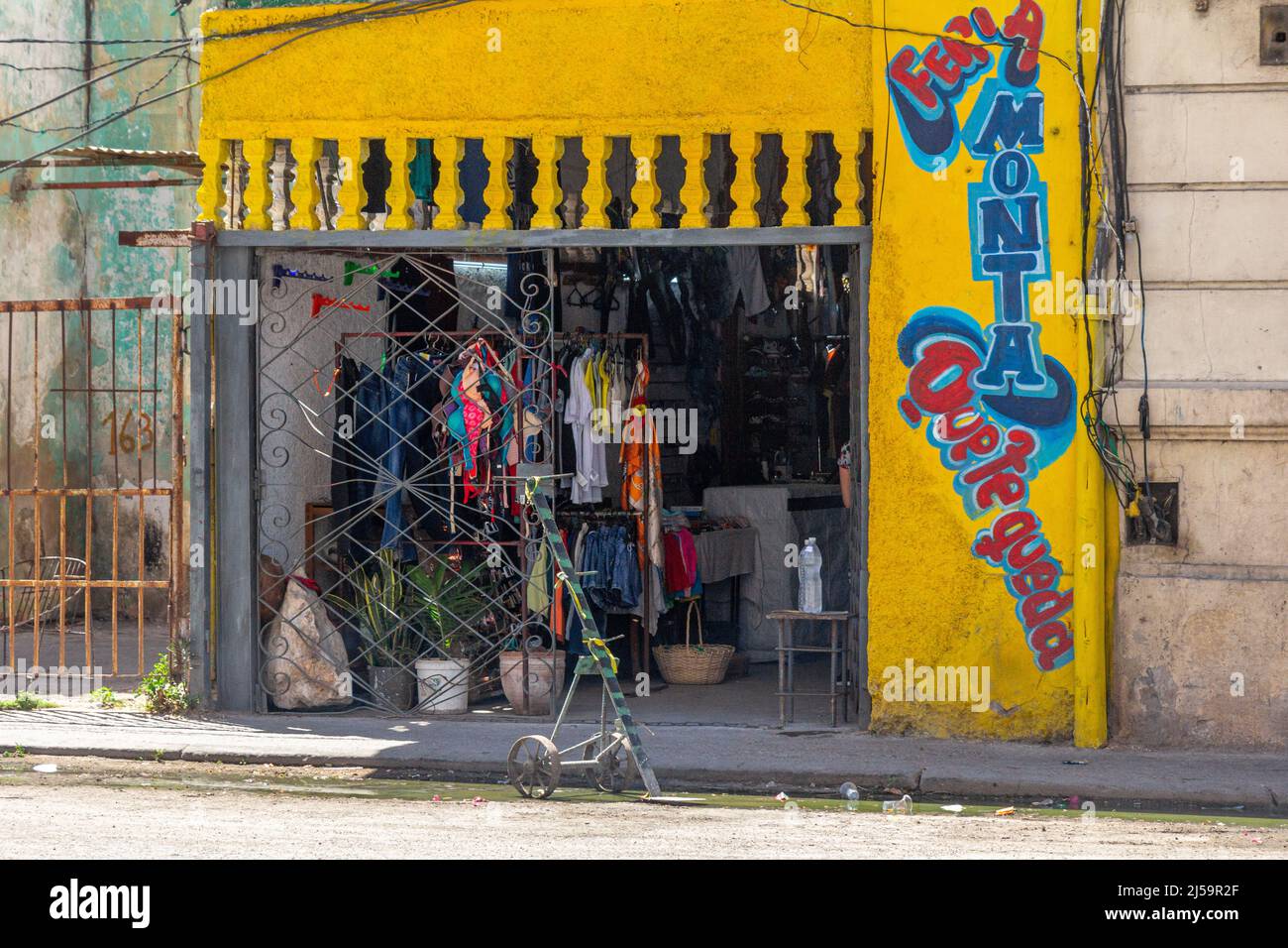 Entrance to a small business set in a former car garage. The door is made of a metallic grid.  A slang Cuban phrase is the name of the place (Feria, m Stock Photo