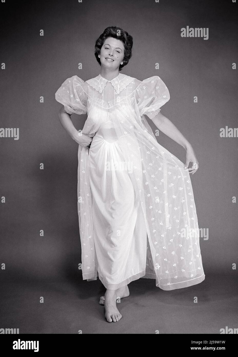 1950s BRUNETTE WOMAN MODELING A SHEER NEGLIGEE SET OF LONG PEIGNOIR WITH  SHORT PUFFY SLEEVES AND A SATIN NIGHTGOWN UNDERNEATH - f836 CRR001 HARS  PERSONS SATIN EXPRESSIONS B&W EYE CONTACT BRUNETTE CHEERFUL