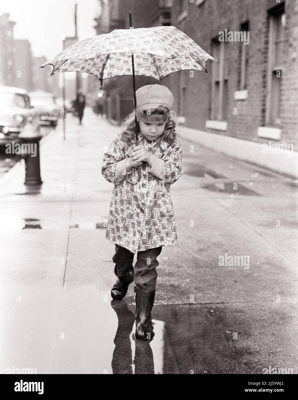 1960s CUTE LITTLE GIRL ON CITY SIDEWALK IN RAIN WEARING RAINCOAT HAT BOOTS CARRYING UMBRELLA CAREFULLY STEPPING INTO A PUDDLE - j11982 HAR001 HARS RAINCOAT WINNING STEPPING HOME LIFE NATURE COPY SPACE FULL-LENGTH RAINY RAINING EXPRESSIONS B&W HIGH ANGLE ADVENTURE DISCOVERY PROTECTION CONCERN CONCEPTUAL CITIES PLEASANT PUDDLES AGREEABLE CAREFULLY CAUTIOUS CHARMING GROWTH JUVENILES LOVABLE PLEASING ADORABLE APPEALING BLACK AND WHITE CAUCASIAN ETHNICITY HAR001 OLD FASHIONED PUDDLE Stock Photo