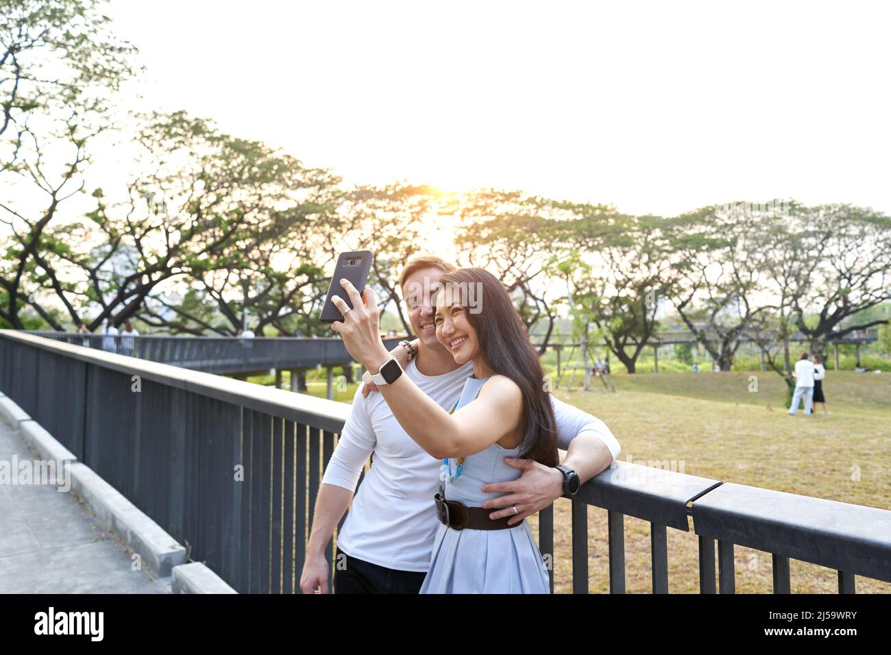Couple taking a selfie from a park during sunset Stock Photo