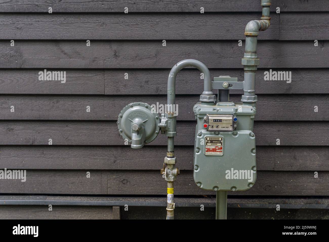 Ontario, Canada, August 2021 - Gas meter and connecting pipes against a wooden wall of a house Stock Photo