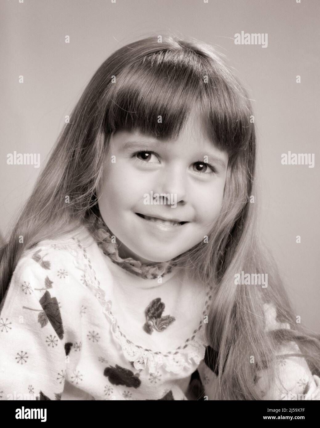 1970s PORTRAIT OF SMILING LITTLE GIRL WITH LONG HAIR AND BANGS LOOKING AT CAMERA - j13181 HAR001 HARS JOYFUL PLEASANT AGREEABLE CHARMING JUVENILES LOVABLE PERSONABLE PLEASING ADORABLE APPEALING BANGS BLACK AND WHITE CAUCASIAN ETHNICITY HAR001 OLD FASHIONED Stock Photo