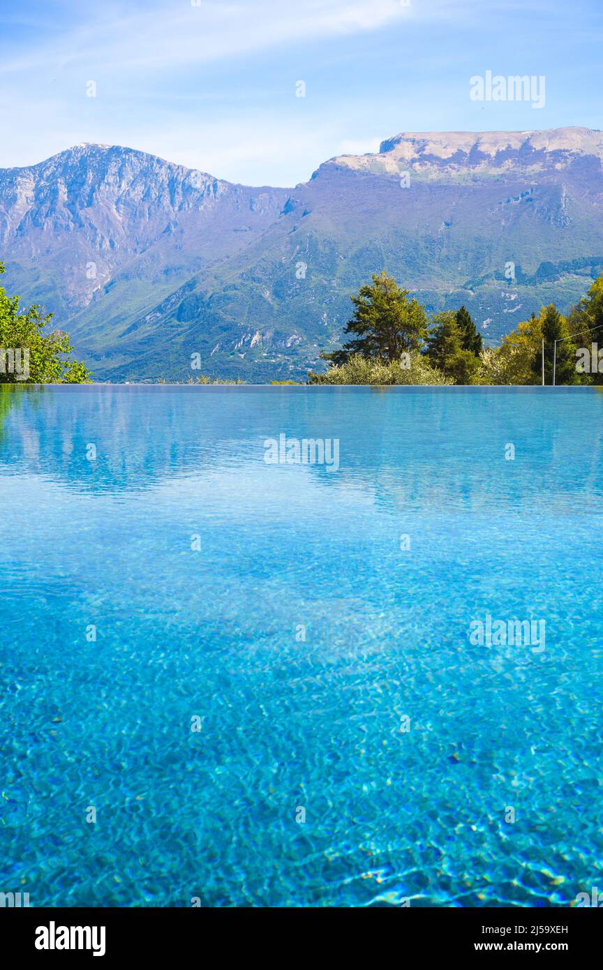 Outdoor infinity swimming pool at luxury hotel with mountains, Garda lake, Italy Stock Photo