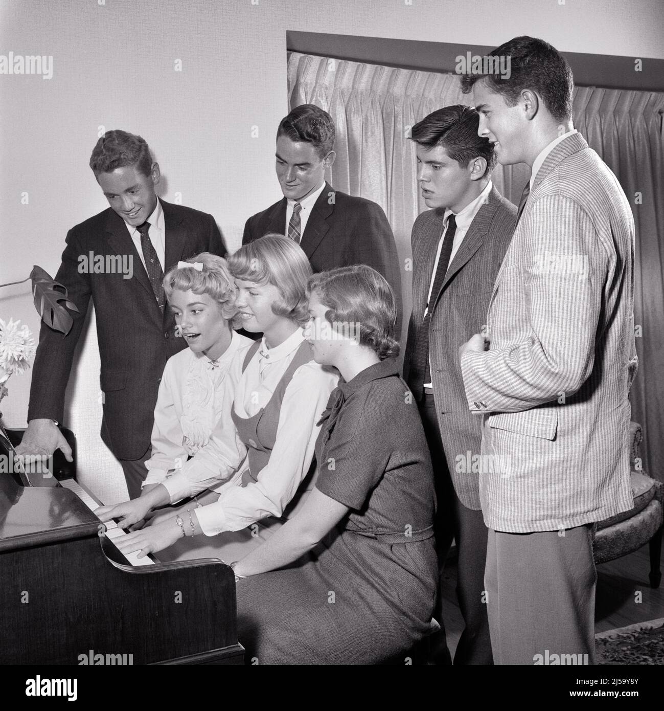 1950s GROUP OF SEVEN TEENAGERS BOYS AND GIRLS AROUND A PIANO PLAYING AND SINGING - j189 HAR001 HARS SINGERS JOY LIFESTYLE SOUND SATISFACTION MUSICIAN CELEBRATION FEMALES HOUSES COPY SPACE FRIENDSHIP HALF-LENGTH PERSONS INSPIRATION RESIDENTIAL MALES TEENAGE GIRL TEENAGE BOY BUILDINGS ENTERTAINMENT B&W SCHOOLS SUIT AND TIE HAPPINESS AND EXCITEMENT RECREATION SONG VOCAL PRIDE OPPORTUNITY ENTERTAINER HIGH SCHOOL HOMES MUSICAL INSTRUMENT HIGH SCHOOLS CONNECTION VOCALIZE CONCEPTUAL VOCALS 7 RESIDENCE SONGS STYLISH TEENAGED CHORAL COOPERATION GROWTH JUVENILES TOGETHERNESS BLACK AND WHITE Stock Photo