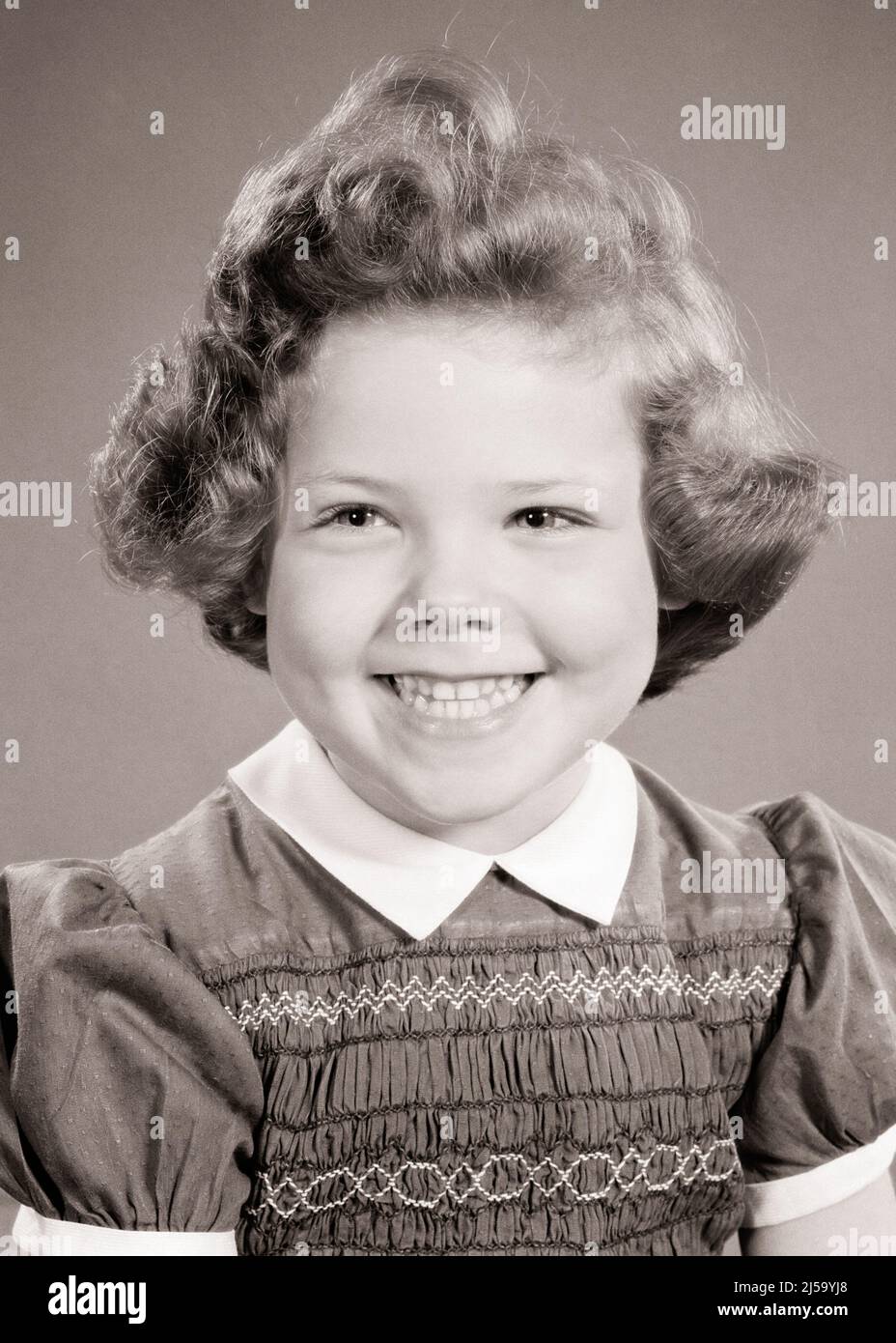 1950s PORTRAIT OF SMILING GIRL LOOKING OFF CAMERA WEARING DRESS WITH EMBROIDERY SMOCKING AND WHITE COLLAR - j3727 HAR001 HARS COPY SPACE CONFIDENCE EXPRESSIONS B&W EMBROIDERY HAPPINESS HEAD AND SHOULDERS CHEERFUL AND EXCITEMENT PRIDE SMILES JOYFUL STYLISH PLEASANT AGREEABLE CHARMING CURL JUVENILES LOVABLE PLEASING ADORABLE APPEALING BLACK AND WHITE CAUCASIAN ETHNICITY CURLY HAIR HAR001 OLD FASHIONED SMOCKING Stock Photo