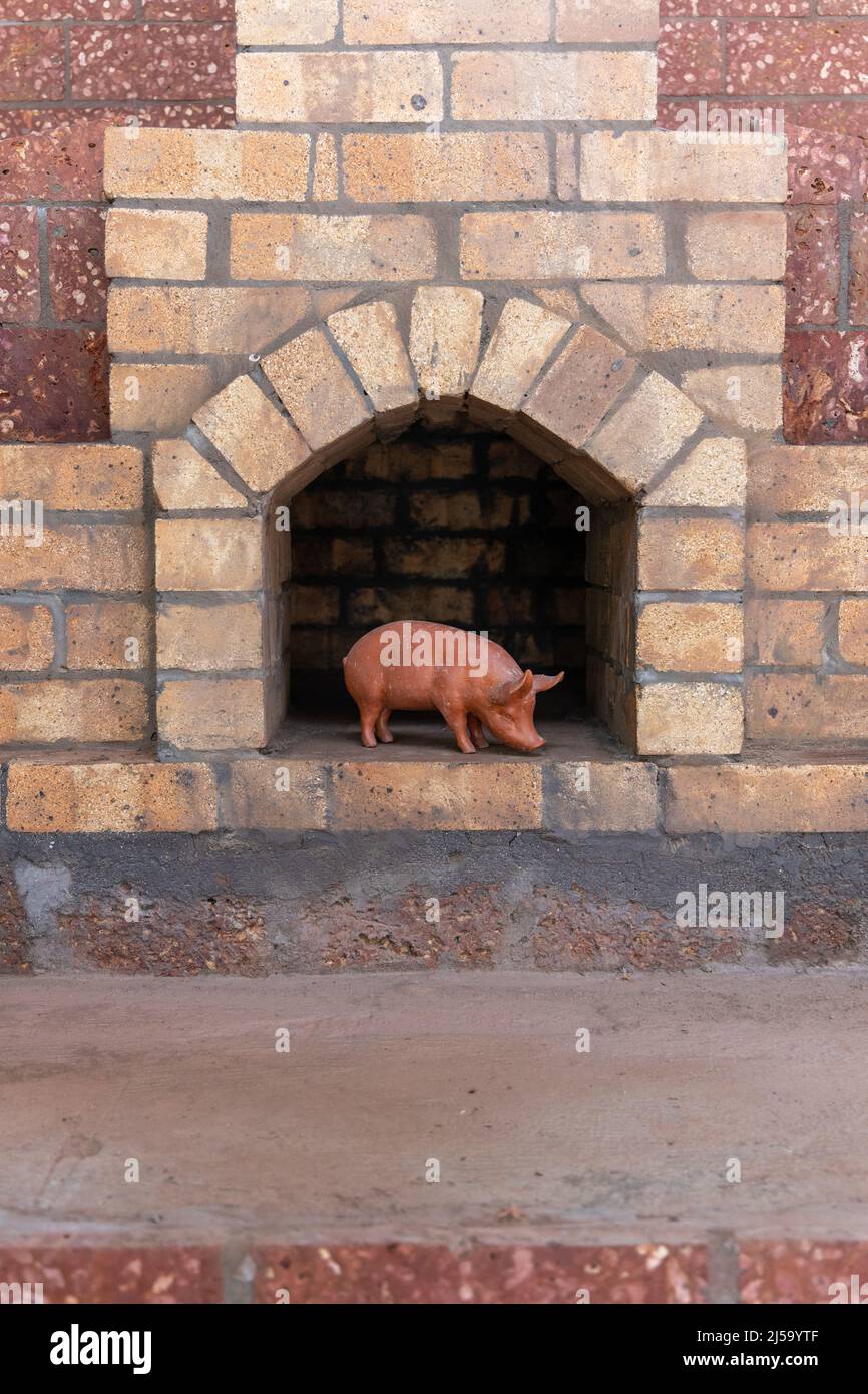 Porcelain Statue Of A Pig Kept In Front Of A Traditional Brick Furnace   Porcelain Statue Of A Pig Kept In Front Of A Traditional Brick Furnace Oven 2J59YTF 