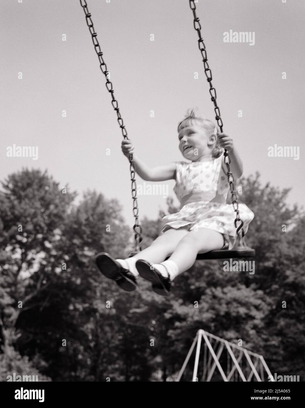 1950s EXCITED SMILING LITTLE GIRL FLYING HIGH ON A PLAYGROUND SWING SET - j7588 HAR001 HARS LIFESTYLE SATISFACTION FEMALES HEALTHINESS HOME LIFE COPY SPACE FULL-LENGTH CONFIDENCE EXPRESSIONS B&W SUMMERTIME FREEDOM DREAMS HUMOROUS HAPPINESS CHEERFUL ADVENTURE LEISURE EXCITEMENT LOW ANGLE COMICAL DIRECTION MARY JANE SMILES SWINGING COMEDY JOYFUL GROWTH HIGH FLYING JUVENILES RELAXATION SEASON BLACK AND WHITE CAUCASIAN ETHNICITY HAR001 OLD FASHIONED Stock Photo