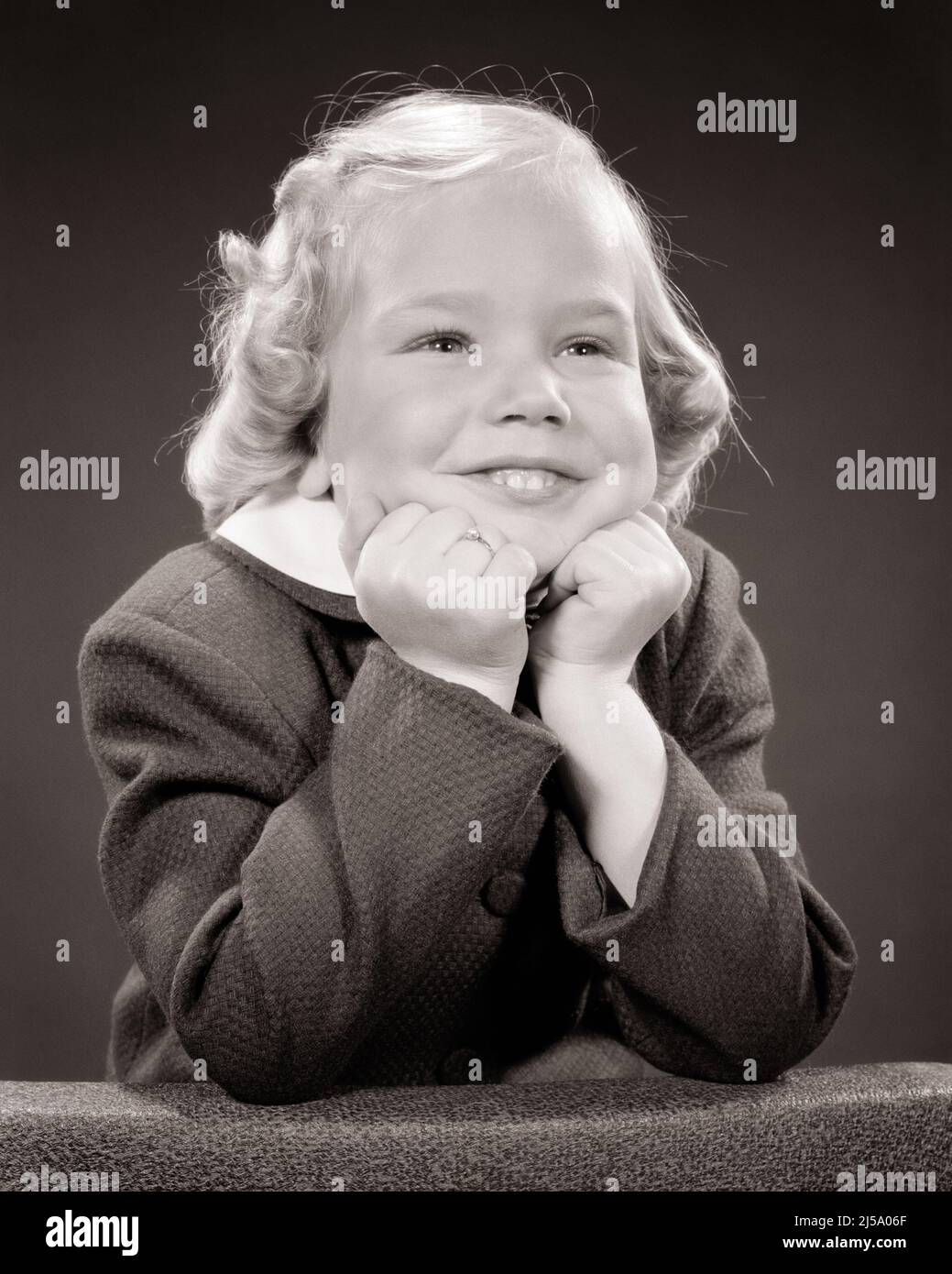 1960s PORTRAIT OF CUTE BLONDE GIRL RESTING HER CHIN ON HER FISTS LOOKING OFF CAMERA WITH AN EXUBERANT VIVACIOUS TOOTHY SMILE  - j7665 HAR001 HARS HALF-LENGTH CHIN CONFIDENCE EXPRESSIONS B&W RESTING GOALS DREAMS HAPPINESS CHEERFUL EXCITEMENT PRIDE FISTS SMILES TOOTHY JOYFUL STYLISH PLEASANT AGREEABLE CHARMING GROWTH JUVENILES LOVABLE PLEASING ADORABLE APPEALING BLACK AND WHITE CAUCASIAN ETHNICITY EXUBERANT HAR001 OLD FASHIONED VIVACIOUS Stock Photo