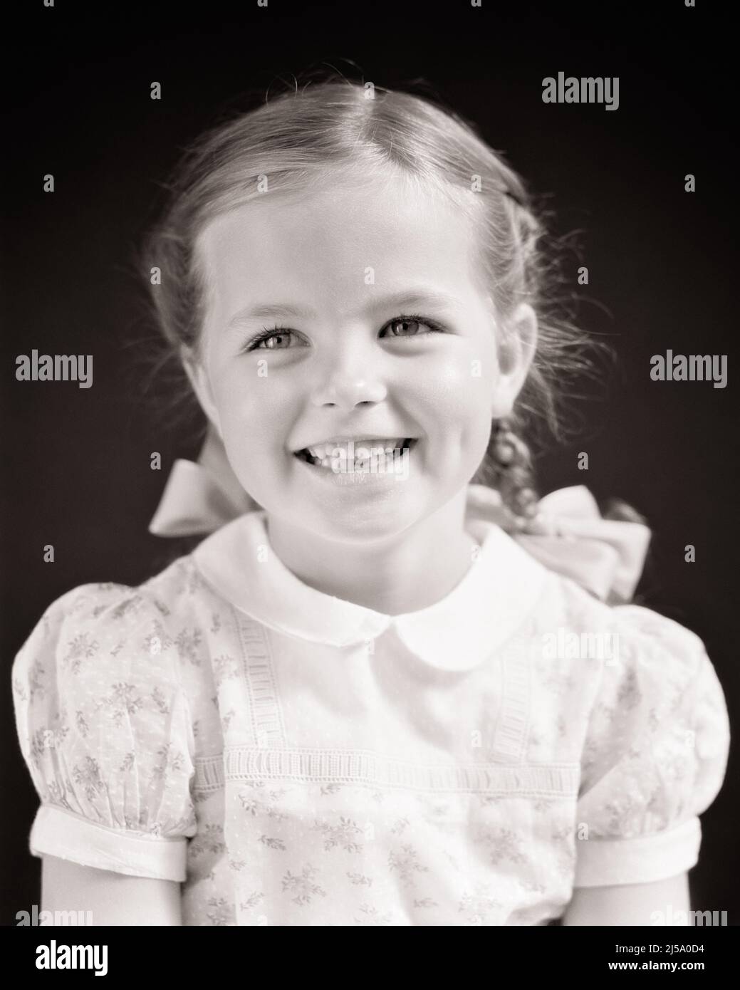 1940s PORTRAIT OF SMILING HAPPY LITTLE GIRL WITH BRAIDED PIGTAILS AND BOWS LOOKING AT CAMERA - j9966 HAR001 HARS HEAD AND SHOULDERS CHEERFUL AND SMILES BRAIDED BOWS JOYFUL STYLISH PLEASANT AGREEABLE CHARMING GROWTH JUVENILES LOVABLE PIGTAILS PLEASING ADORABLE APPEALING BLACK AND WHITE CAUCASIAN ETHNICITY HAR001 OLD FASHIONED Stock Photo