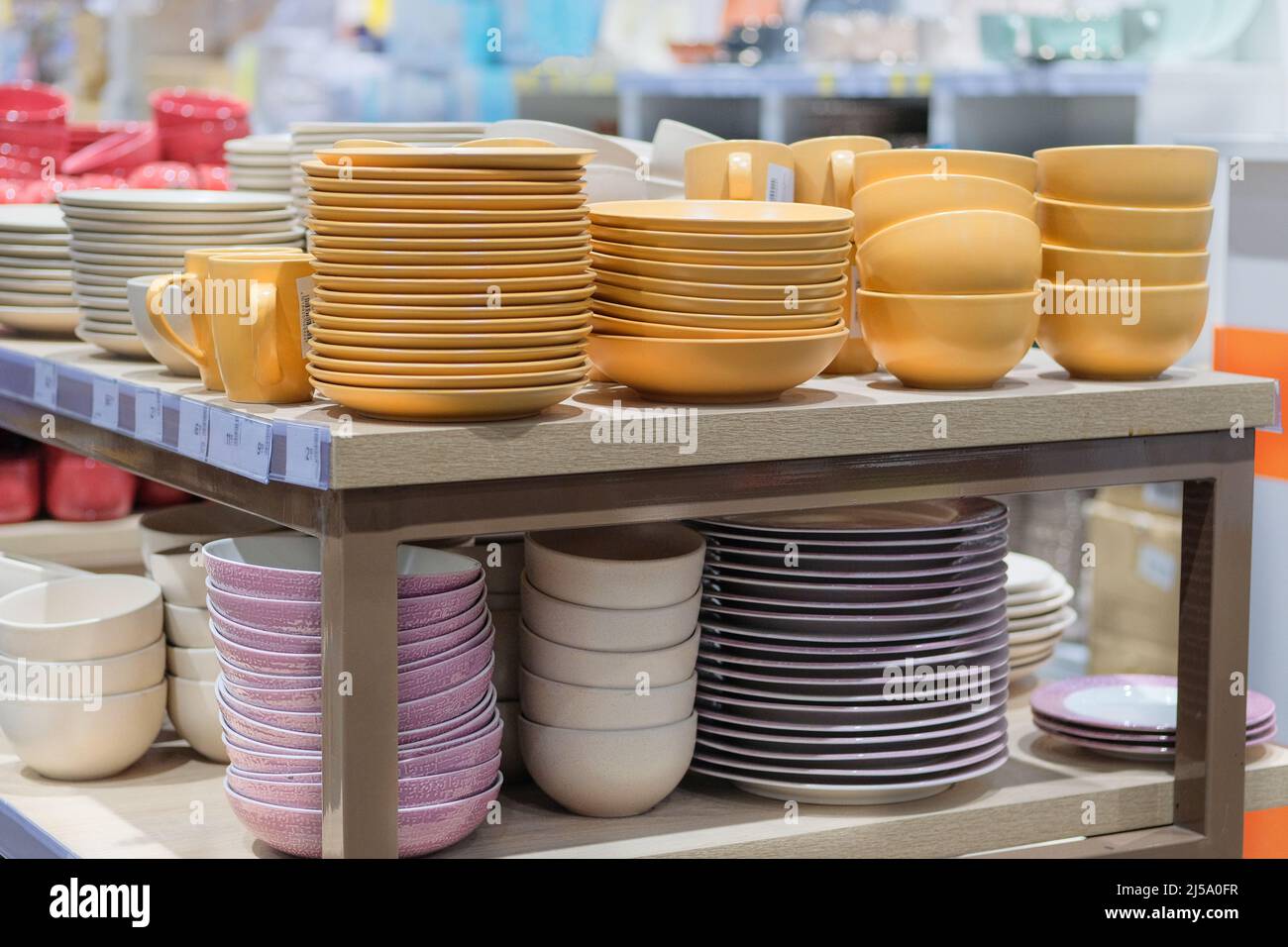 Dishes are sold at the store. Rows of different yellow bowls and plates for home on shelves in a