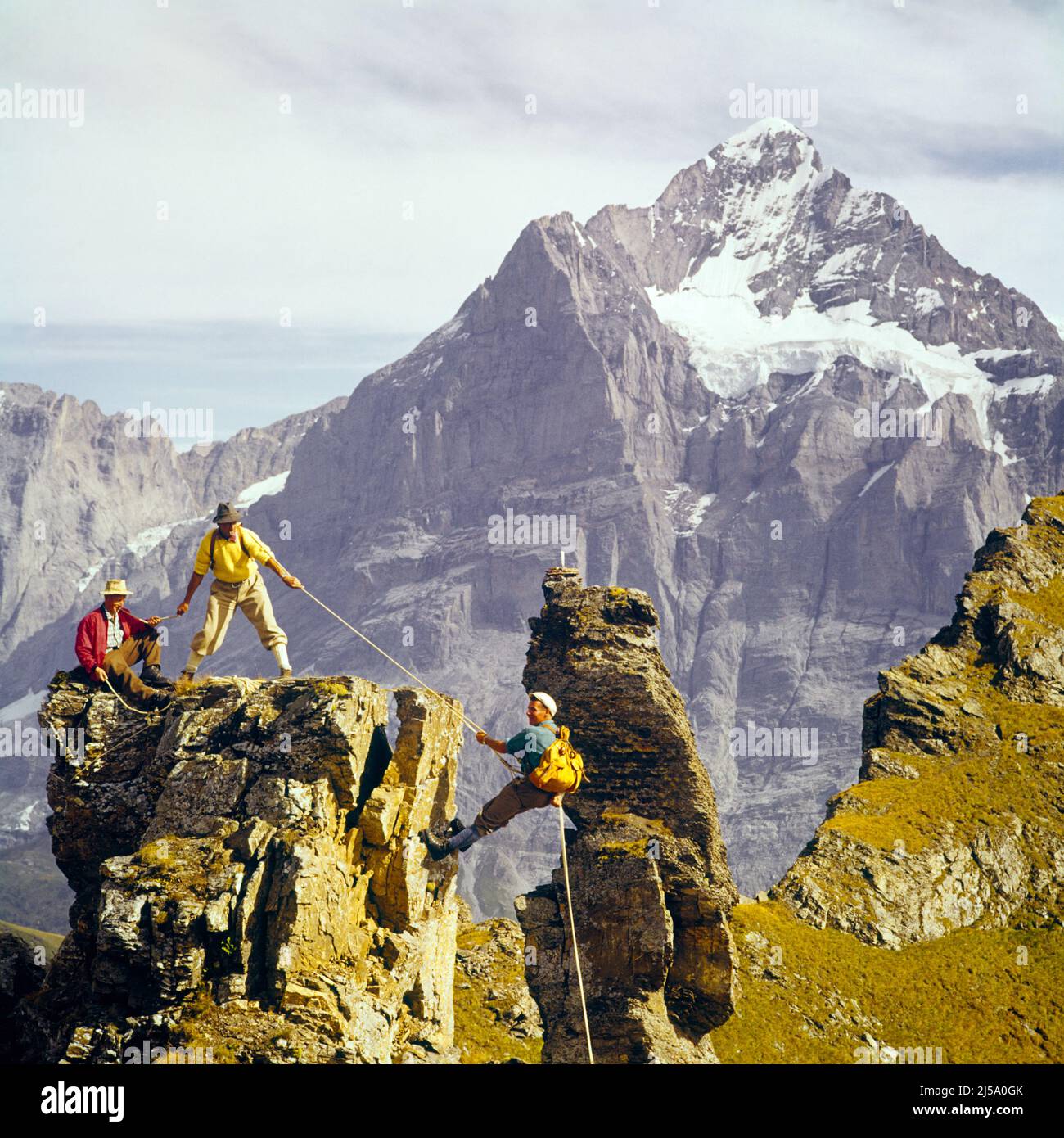 1960s THREE MEN USING ROPES FOR CLIMBING AND RAPPELLING IN SWISS ALPS ...