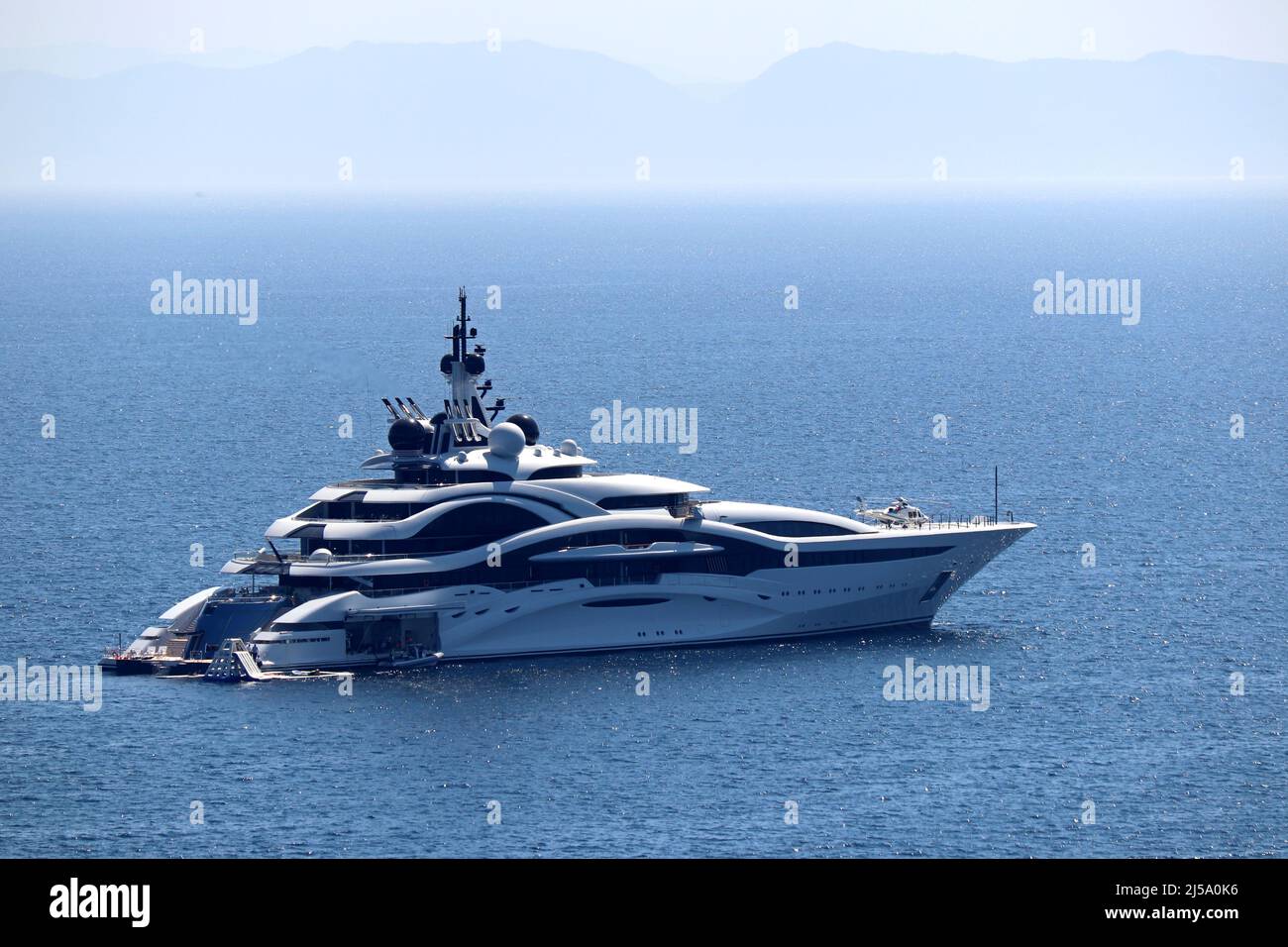 Luxury yacht with helipad and helicopter sailing in a sea, side view