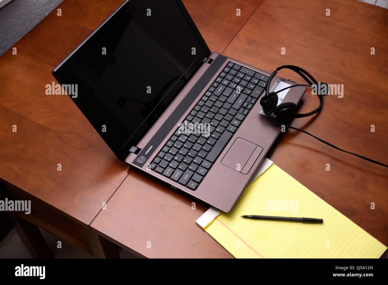 Open laptop computer with yellow pad and pen nearby for making notes. Stock Photo