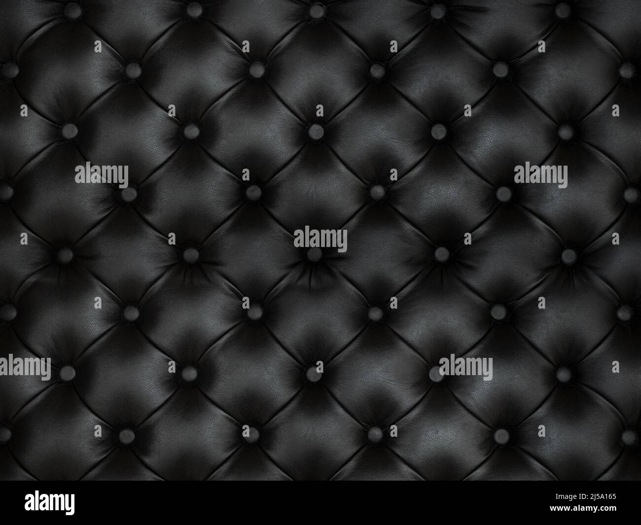 upholstery of leather buttoned black color fabric, wall pattern. Elegant vintage quilted sofa background. Interior Stock Photo