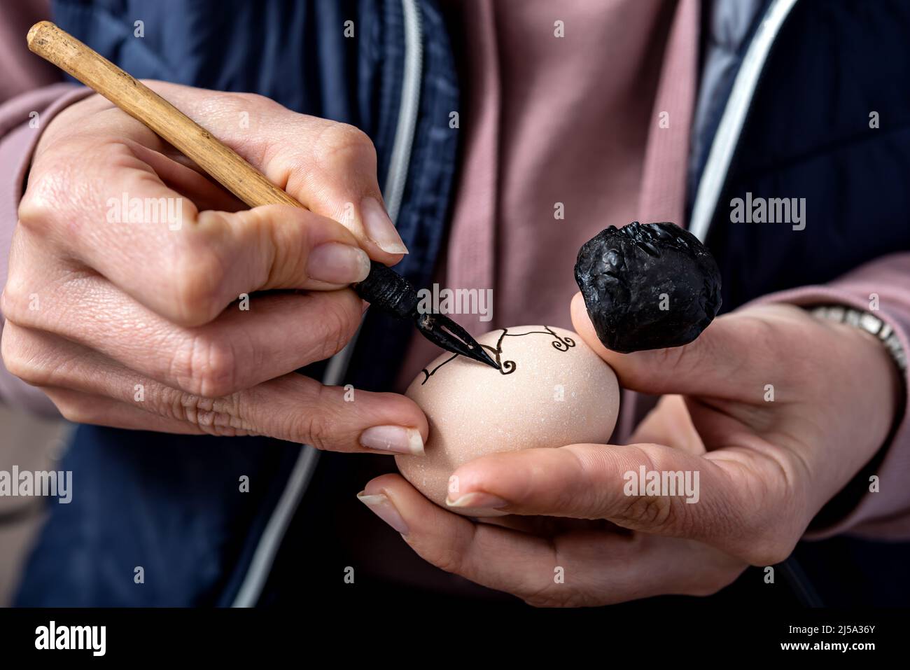 Female hands traditionally paint eggs with floral patterns using a