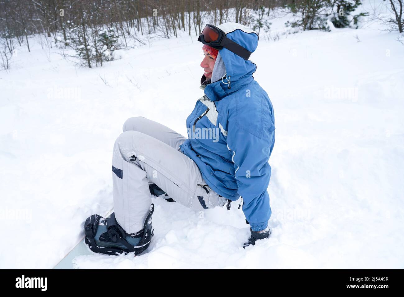 A guy with a snowboard is resting sitting on the snow Stock Photo