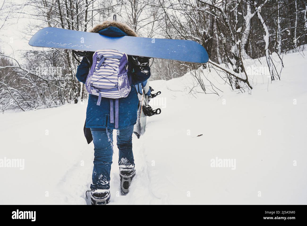 The girl goes with a snowboard vrkah on a snowy slope Stock Photo