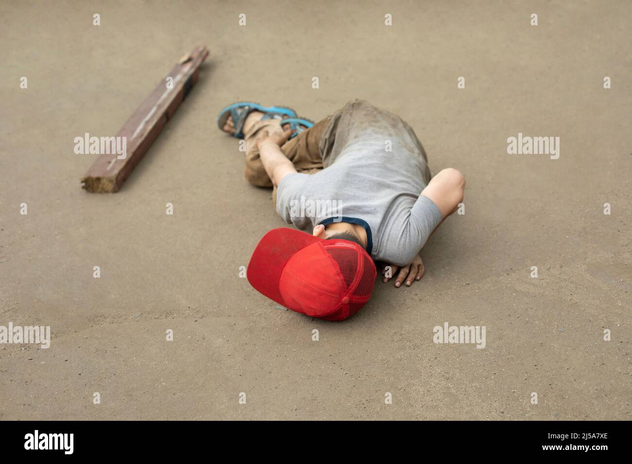 The child fell to the asphalt. Dangerous fall of the child. The boy lies and does not move. The son stumbled. Bad student behavior. Stock Photo
