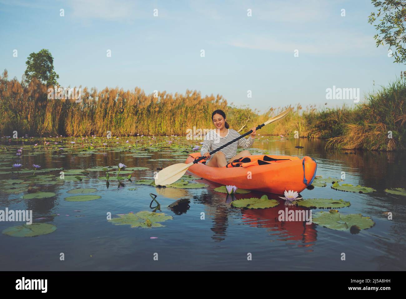 asian younger woman sailing sea kayak in lotus flower lagoon with happiness Stock Photo