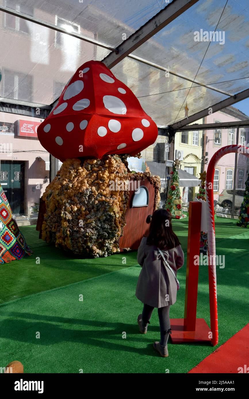 little girl walking to a mushroom house, santa village by christmas time. Magical world for kids. Stock Photo