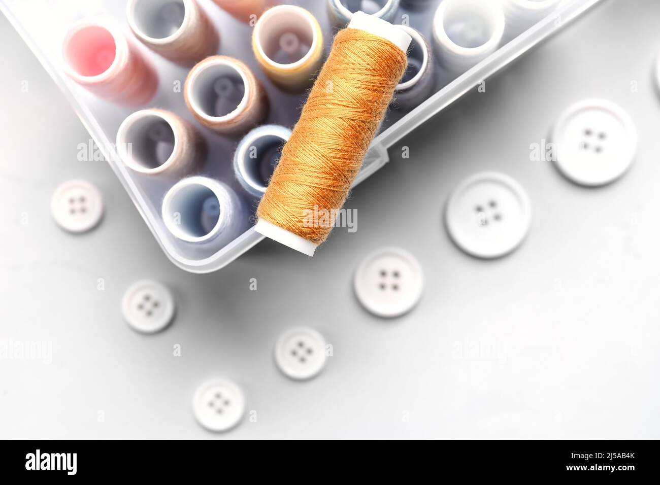 Box with sewing threads and buttons on light background Stock Photo - Alamy