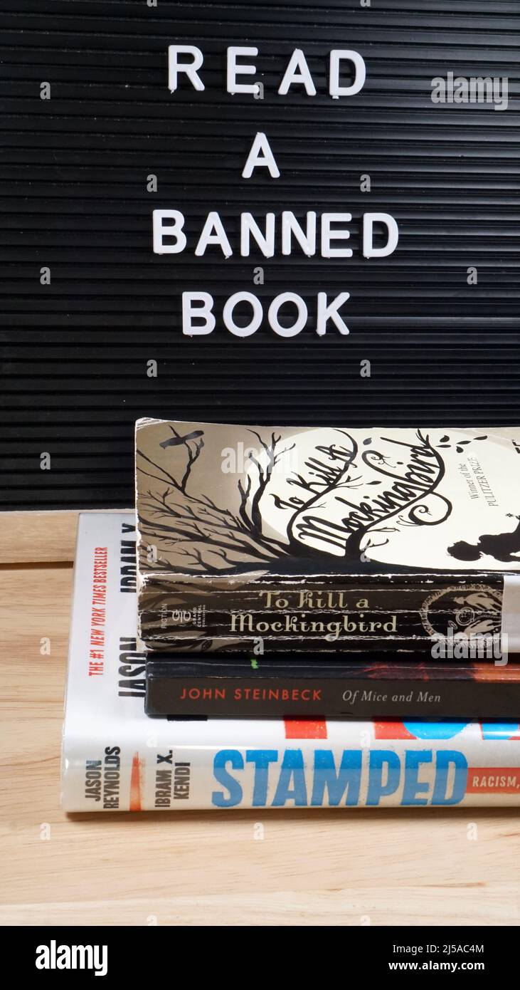 Reminder to read a banned book, along with copies of oft-banned books To Kill a Mockingbird, Stamped, and Of Mice and Men. Stock Photo